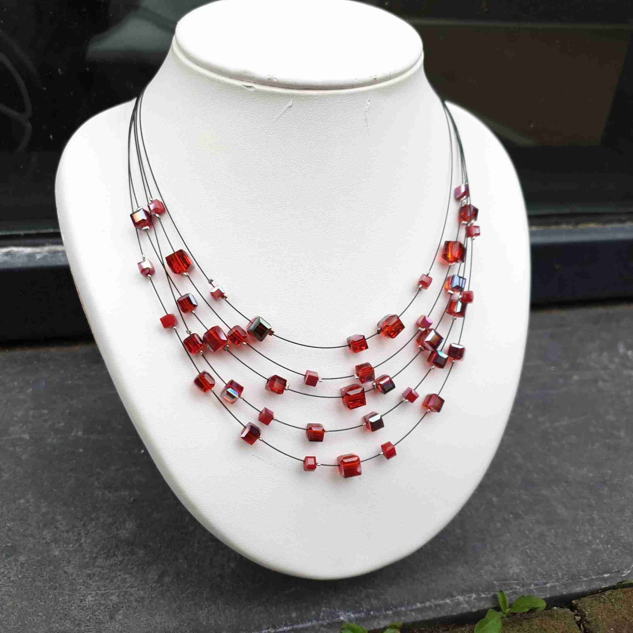 Mooie ketting van staaldraad met kleine blokjes in rood